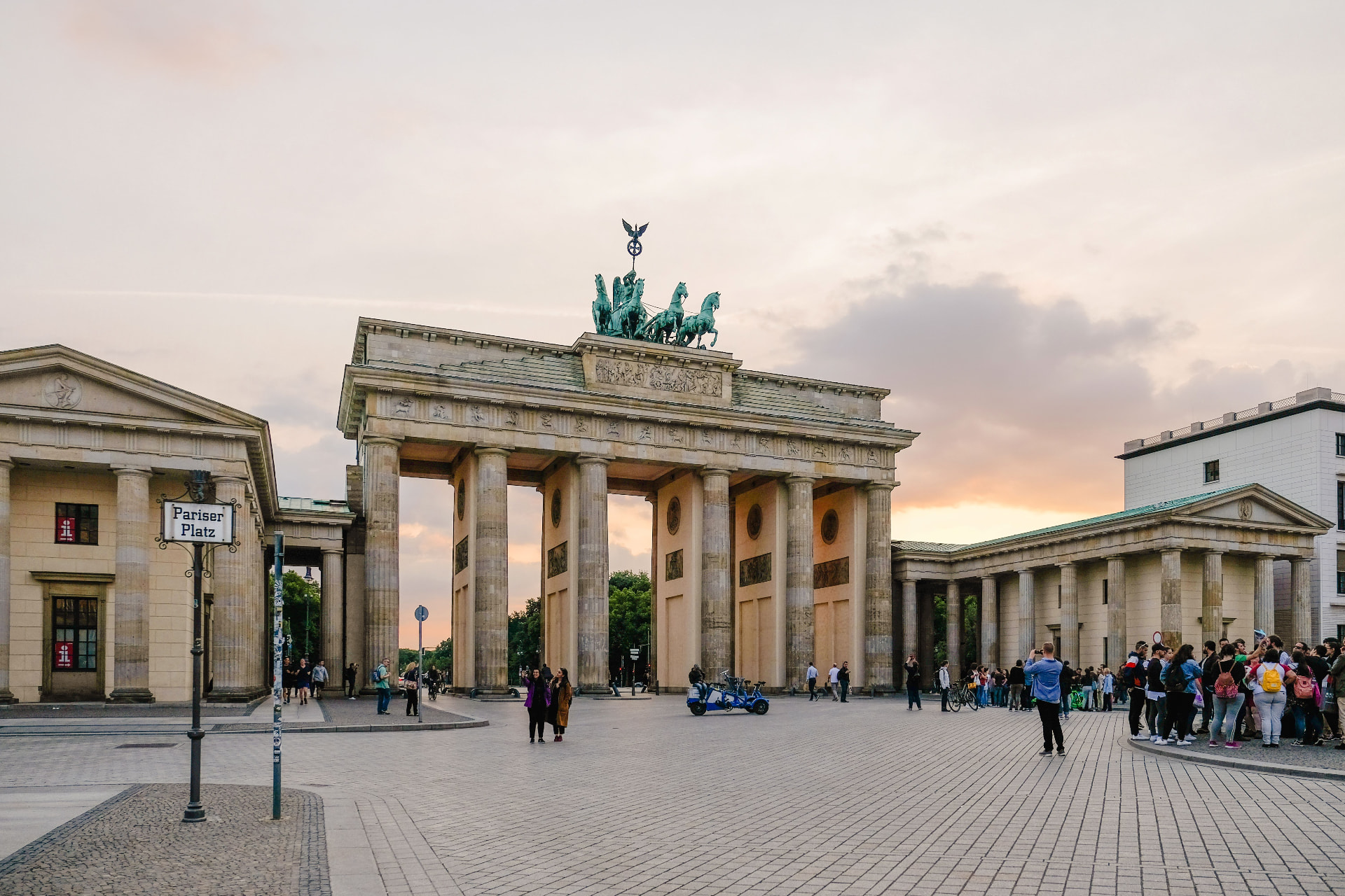 The Brandenburg Gate on Pariser Platz in Berlin at sunset, with the quadriga on top and visitors crossing the square